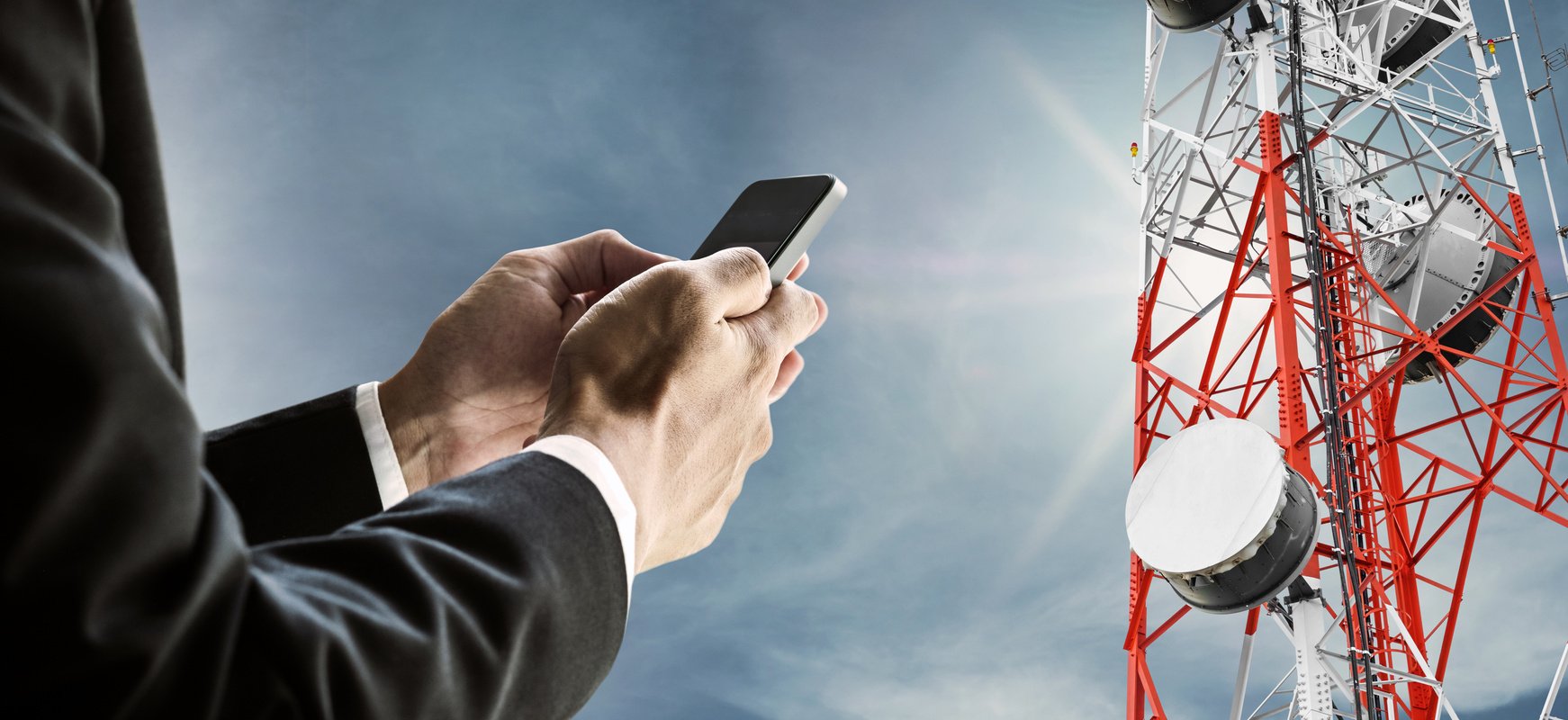 Businessman using mobile phone, with satellite dish telecom network